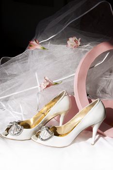 Wedding shoes, box and veil over dark background