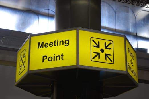 yellow and black meeting point sign at a international airport