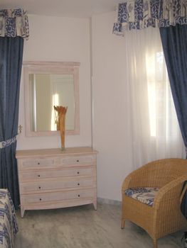 chest of draws and chair infront of a mirror of a bedroom interior