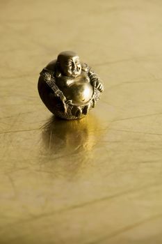 Buddha statue with big belly on shiny gold background