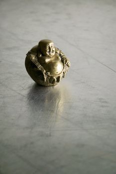 Buddha statue with big belly on shiny silver background