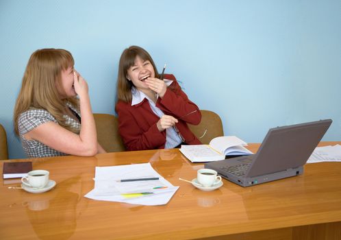 Young girls laugh sitting at a table