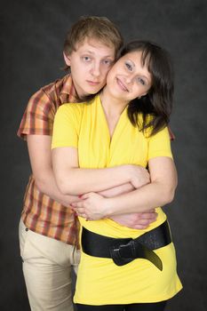 Young couple embraces on a black background