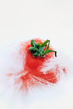 Tomato frozen in ice cube, isolated on white background
