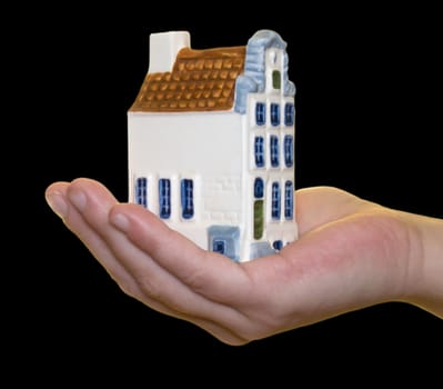 Miniature house in hand on a black background