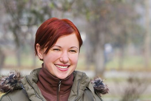 Redhead girl smilling in an autumn park.Shot with Canon 70-200mm f/2.8L IS USM