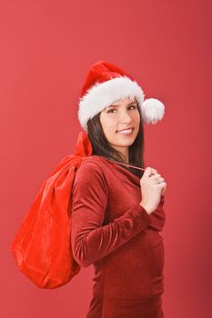 Beautiful Christmas girl with gifts sack against a red background.