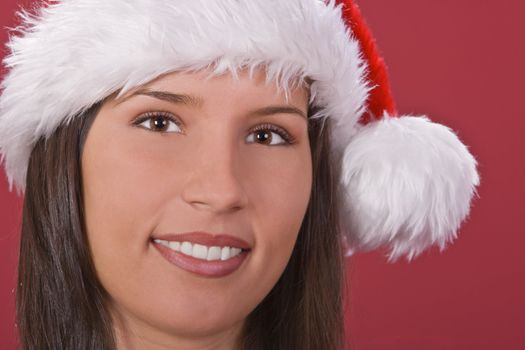 Portrait of a girl wearing a Santa's hat against a red background.