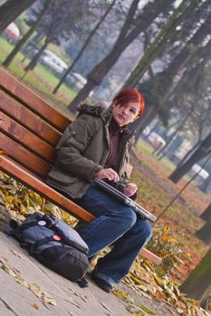 Image of a redheaded teen sitting on a bench in an autumn park.Shot with Canon 70-200mm f/2.8L IS USM