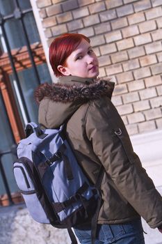 Image of a redheaded girl student with a backpack in front of the University building.Shot with Canon 70-200mm f/2.8L IS USM