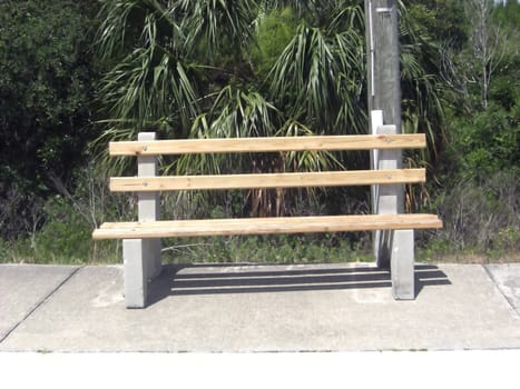 A lonely park bench has a forest as a background.