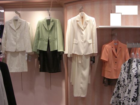 A retail store has various displays of ladies smart wear hanging on the wall.