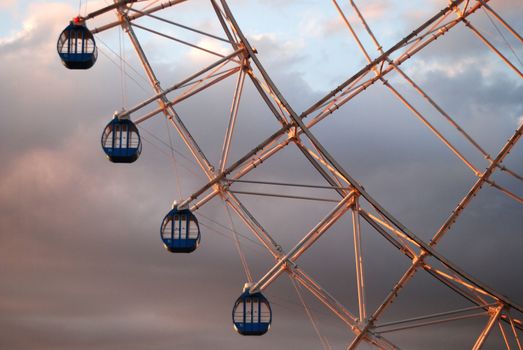 Close up of section of Ferris Wheel. four gondolas against cloudy sky