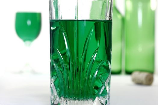 Glass with green wine and green wine background