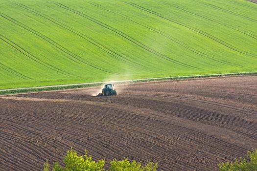 tractor throwing up dust on farmland