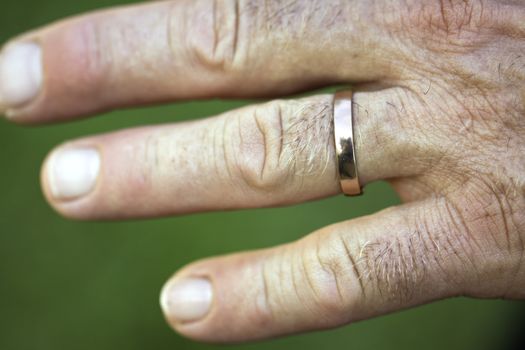 A closeup of a hand of a man with a golden wedding ring on his ring finger