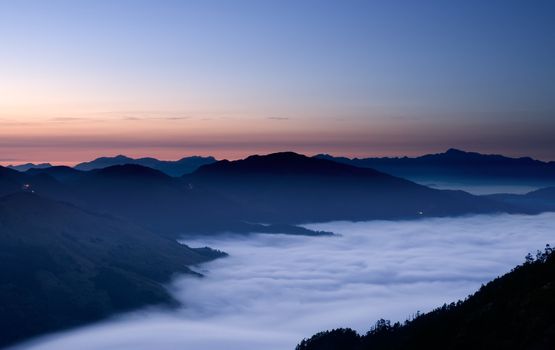 It is a peaceful mountain with clouds in night.