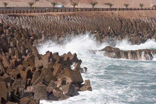 Wave crashing on the shore protected by breakwater at Arica harbor, Chile