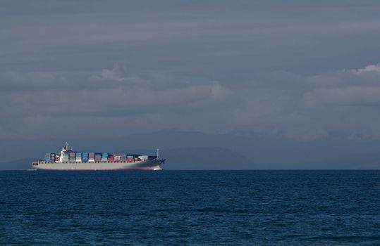 Loaded Freighter on the Juan de Fuca straits with mountains and clouds in background