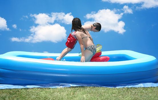 Siblings playing in a swimming pool together