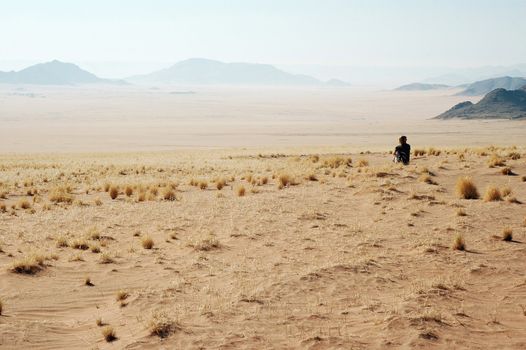 Woman look at the desert - Desert Mountains background. Namibia, Deadvlei, Sossuvlei.