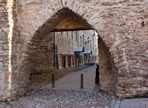 Old archway leads to path by stone houses in Tallinn in Estonia