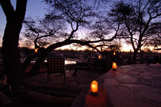 Beautiful african sunset, with swimming pool and acacia tree silhouette.