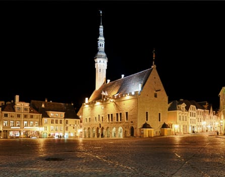 Tallinn town hall at night in Raekoya square showing the floodlit spire and tower of the hall