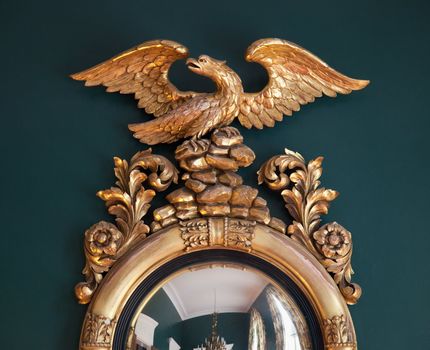 Carved eagle on the top of a convex carved golden frame of a mirror