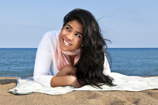 Portrait of beautiful smiling native american girl laying at beach looking up