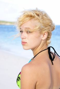 A closeup shot of a young girl in a bikini who is at the beach.