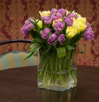 Bouquet of yellow and violet tulips in the glass vase