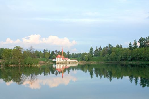 On the shore of the lake is visible Priory Palace and its reflection in the water, Gatchina, Russia.