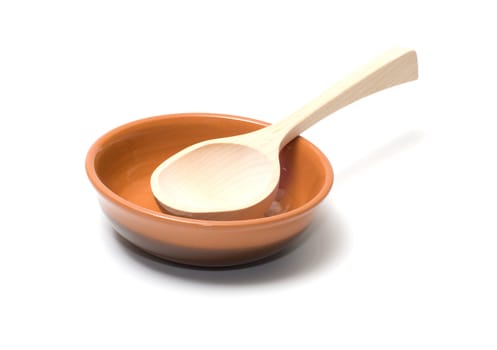 Wooden spoon in a brown ceramic plate.