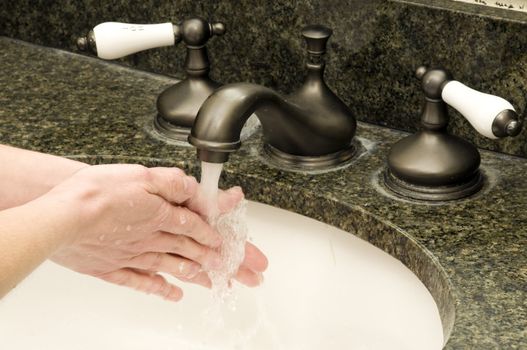 a woman washes her hands with soap and water