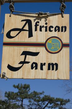 hanging wooden farm sign against a blue sky