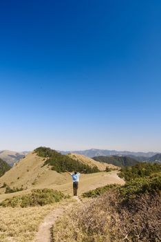 A man stand in the beautiful yellow grassland and blue sky outdoor.