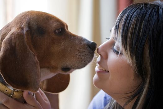 A pretty young woman posing with her beagle pup. Shallow depth of field.