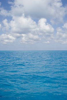 Portrait oriented background image of blue ocean water with a partly cloudy sky