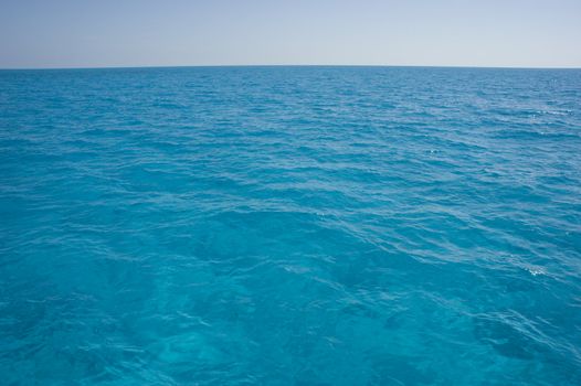 Landscape oriented background image of blue ocean water with a clear sky