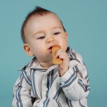 adorable 8 months cacasian baby boy eating a cookie