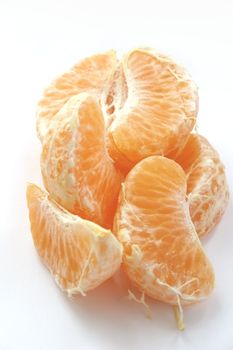 fresh orange split into pieces over a white background