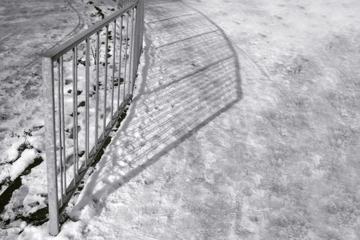 long railing shadows across compacted snow