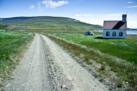 Country sandy route and white wooden church in Unadsdalur - Iceland