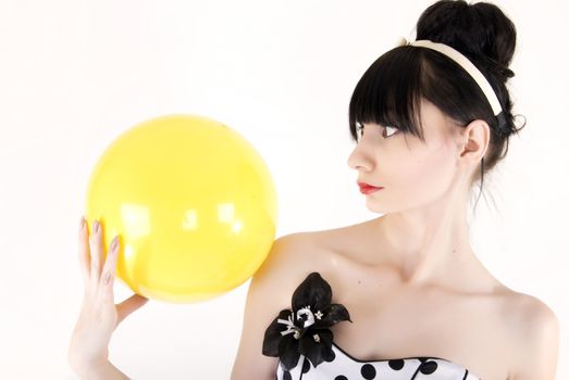 Portrait of a young beautiful brunette posing with yellow ball