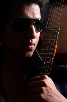 A portrait of a handsome young Indian guitarist.