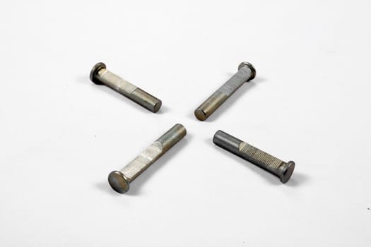 Four bolts of an industrial machine, on a white fabric.