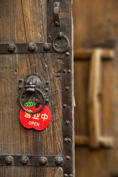 finely decorated chinese wooden old door with a red open sign