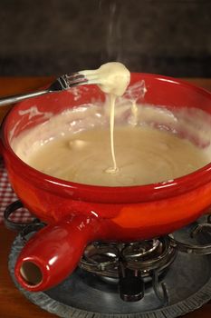 Bread being dipped into the melted cheese in the fondue bowl.