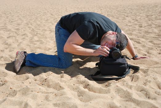Photographer on the beach using a bag to place his camera.